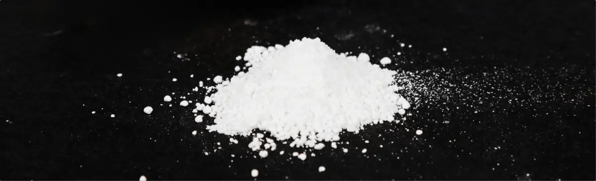 Pile of cocaine in the form of white powder on dark table.