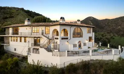 Modern white luxury rehab villa in Los Angeles hills with arched windows, balconies, mountain views, and private pool at Wattles Estate