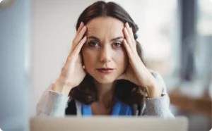 Stressed female executive holding her head, illustrating the need for trauma treatment for professionals.