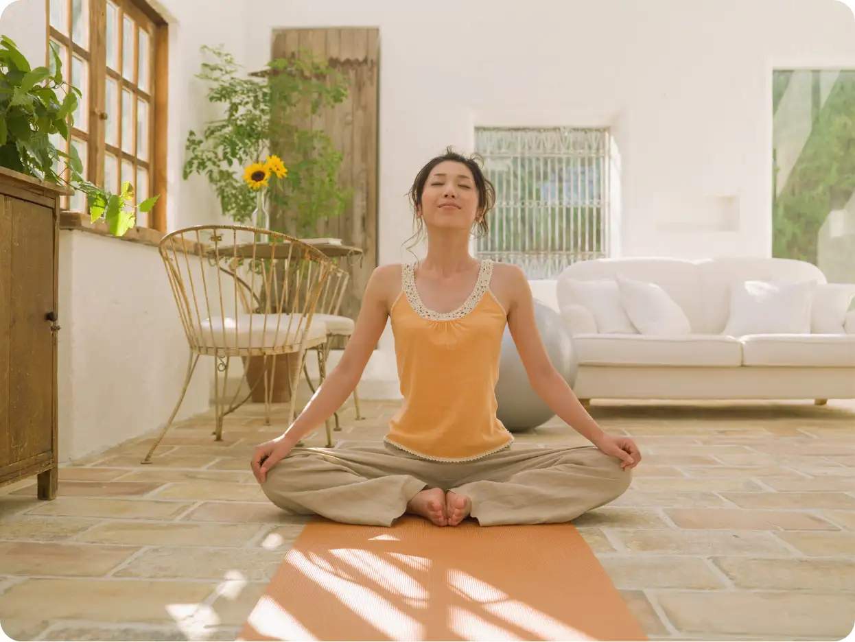 A woman sitting in a meditative yoga pose in a bright, serene studio. This image showcases the mind-body interventions for emotional regulation used in our recovery programs to help clients manage stress and restore balance.